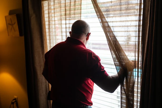 Dennis checking a window from inside a home